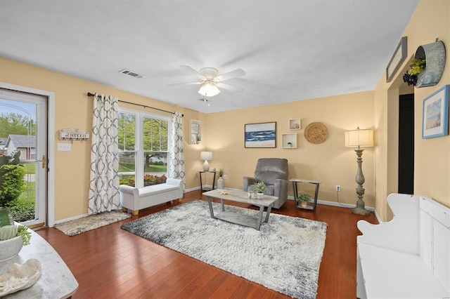 living area featuring baseboards, visible vents, wood finished floors, and a ceiling fan