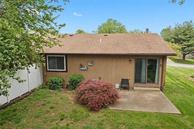 rear view of house with fence, a patio area, a yard, and a shingled roof