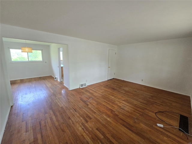 empty room featuring visible vents and dark wood-style floors