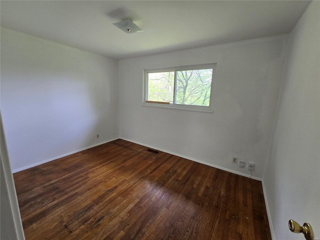 spare room with baseboards, visible vents, and dark wood-type flooring