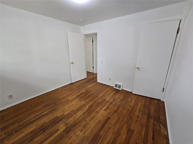 empty room with baseboards, dark wood finished floors, and visible vents