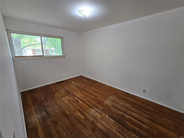 empty room with baseboards, dark wood finished floors, and visible vents