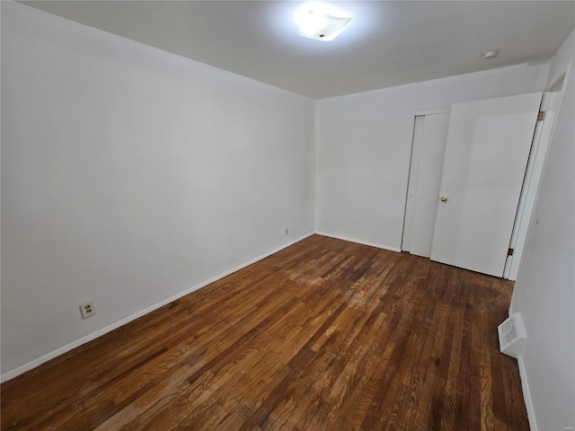 empty room featuring visible vents, dark wood finished floors, and baseboards