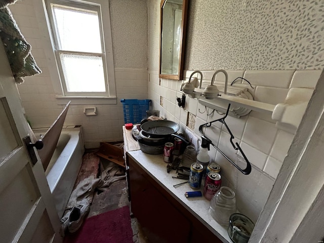 full bath featuring tile walls, a tub, and wainscoting