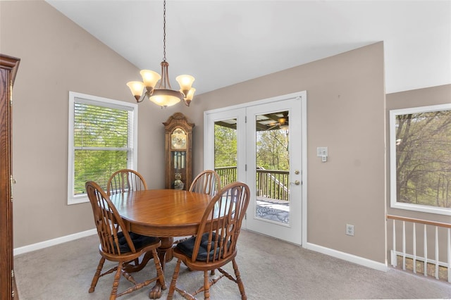 dining room with light carpet, vaulted ceiling, a chandelier, and baseboards