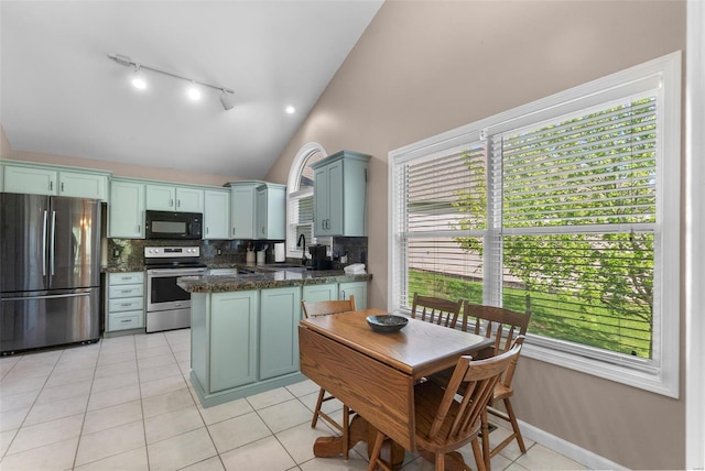 kitchen featuring track lighting, decorative backsplash, stainless steel appliances, a sink, and a peninsula