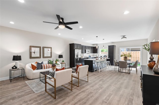 living area featuring recessed lighting, baseboards, ceiling fan, and light wood finished floors