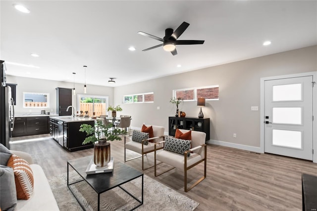 living area with a ceiling fan, baseboards, recessed lighting, and light wood-type flooring