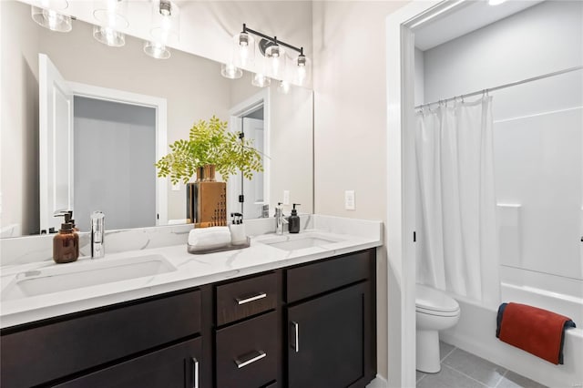 bathroom with a sink, tile patterned flooring, toilet, and double vanity