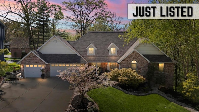 view of front of property with brick siding, a garage, roof with shingles, and driveway