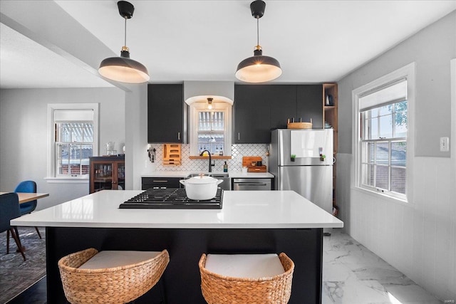 kitchen with gas cooktop, light countertops, freestanding refrigerator, marble finish floor, and dark cabinets