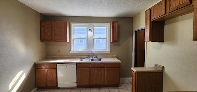 kitchen with brown cabinetry, a textured ceiling, dishwasher, and a sink