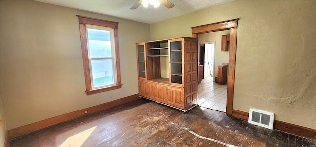 unfurnished room with baseboards, visible vents, ceiling fan, and dark wood-type flooring