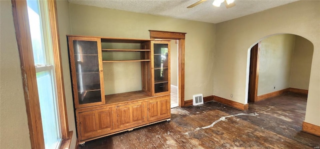 interior space with arched walkways, hardwood / wood-style flooring, visible vents, a ceiling fan, and a textured ceiling