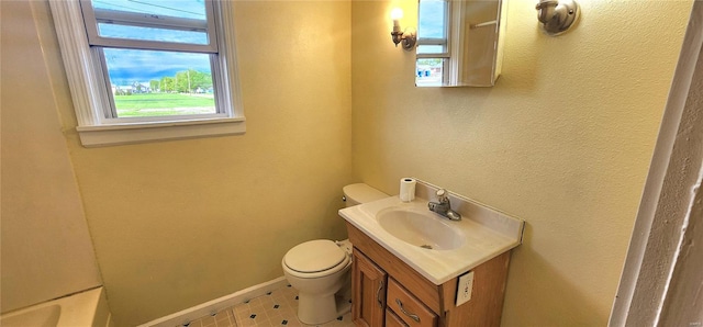 bathroom with toilet, a wealth of natural light, vanity, and baseboards