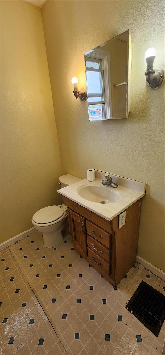 half bath featuring toilet, vanity, and baseboards