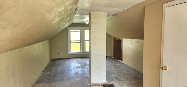 additional living space with ornate columns, a textured ceiling, lofted ceiling, and a textured wall