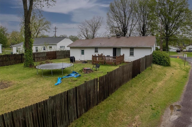 rear view of property with a lawn, a fire pit, a wooden deck, and a fenced backyard