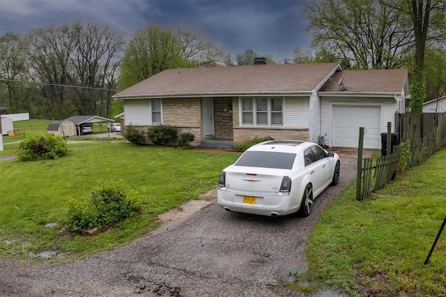 ranch-style house with fence, an attached garage, a front lawn, and aphalt driveway