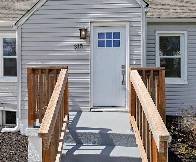 entrance to property featuring a shingled roof