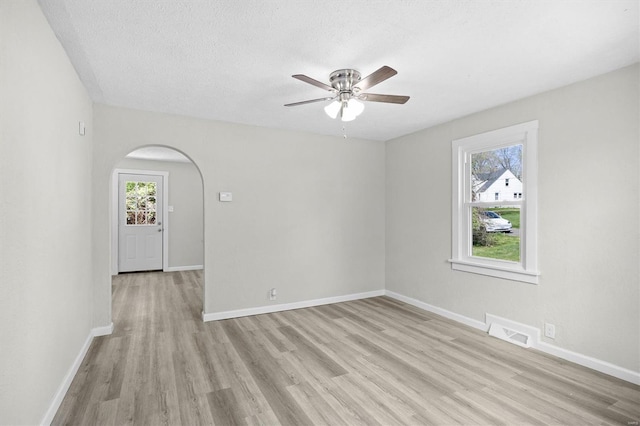 empty room with visible vents, ceiling fan, light wood-style flooring, and baseboards