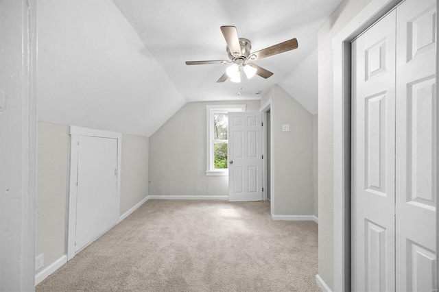 additional living space with lofted ceiling, light colored carpet, a ceiling fan, and baseboards