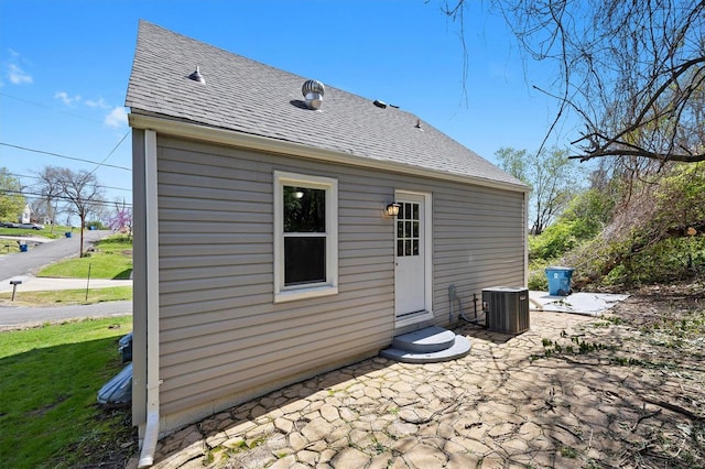 rear view of house with roof with shingles, central AC, a patio area, and entry steps