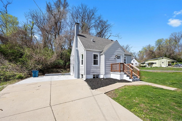 view of home's exterior with a chimney, a shingled roof, concrete driveway, and a lawn