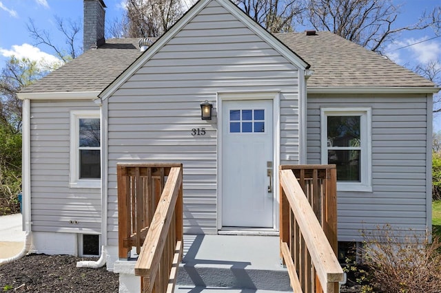 exterior space with a chimney and roof with shingles
