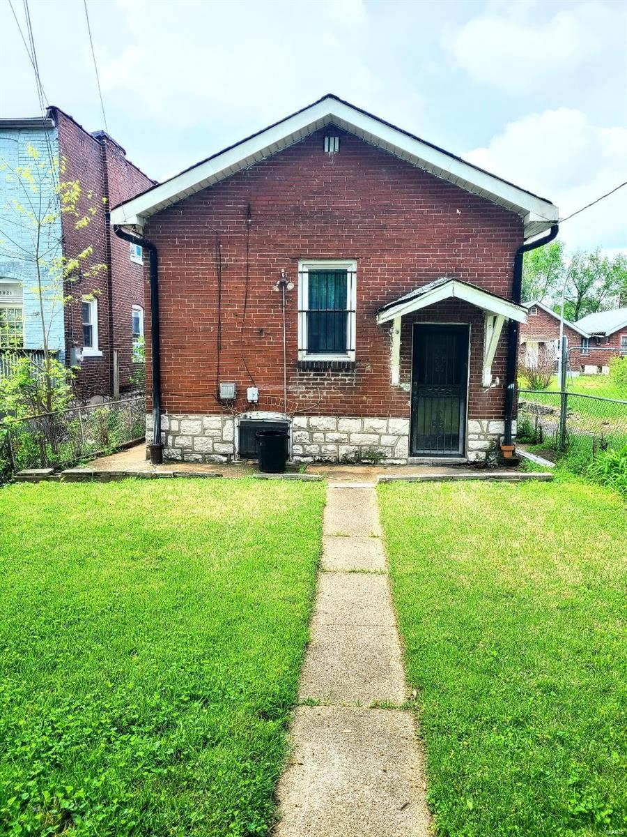 view of front facade with fence, brick siding, and a front lawn