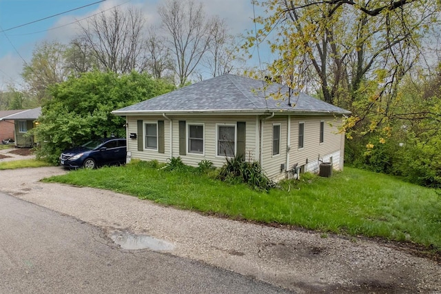 view of property exterior with a lawn, central AC unit, and roof with shingles