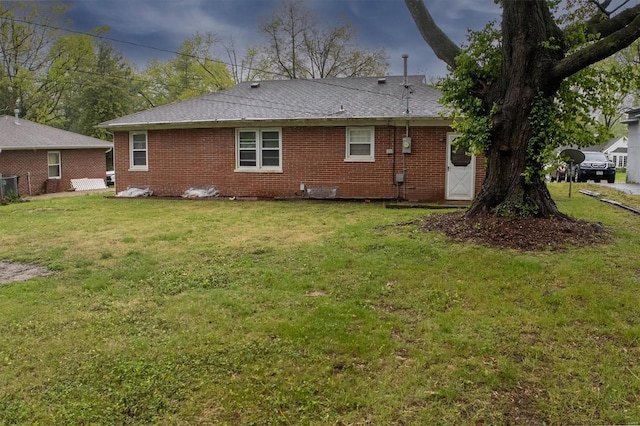 rear view of property featuring a yard and brick siding
