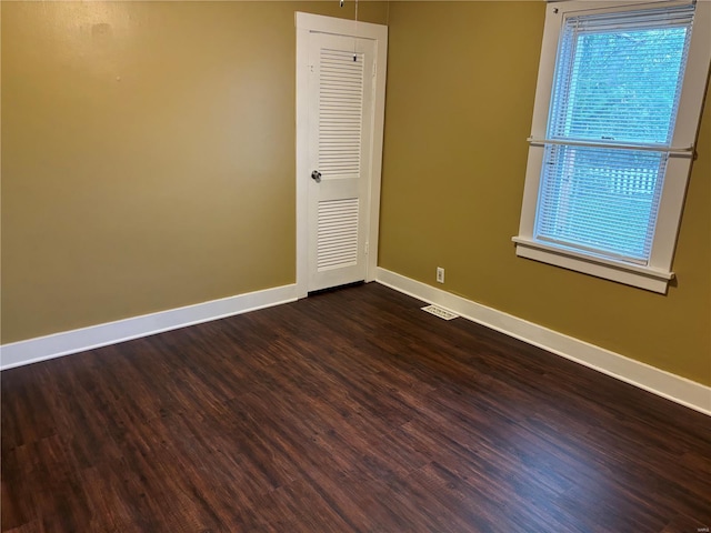 empty room featuring baseboards, visible vents, and dark wood-type flooring