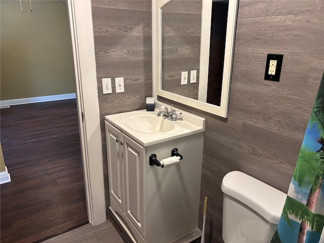 bathroom featuring vanity, baseboards, wood finished floors, and toilet