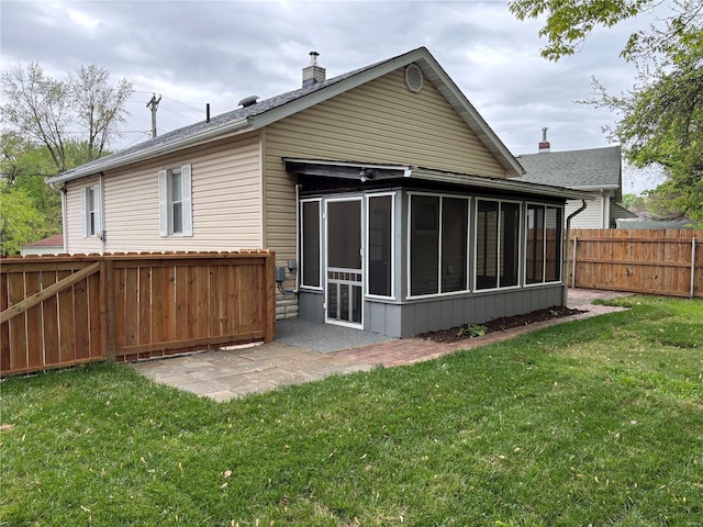 rear view of property featuring roof with shingles, a sunroom, a fenced backyard, a chimney, and a yard