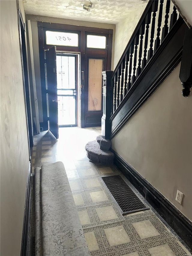 entryway with stairs, baseboards, and visible vents