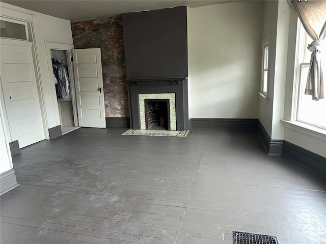 unfurnished living room with baseboards, a fireplace with flush hearth, and visible vents