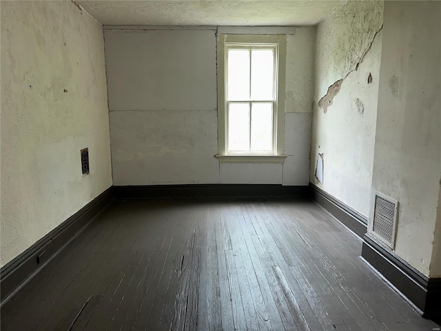 empty room with visible vents and hardwood / wood-style floors