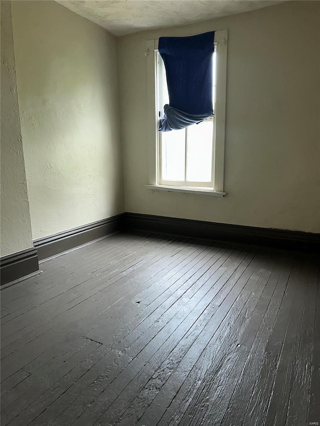 unfurnished room with baseboards and wood-type flooring