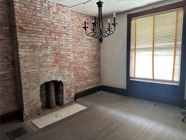 unfurnished living room featuring baseboards, visible vents, wood finished floors, and an inviting chandelier