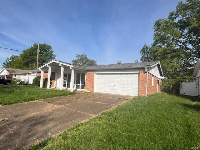 view of front of property featuring a front lawn, driveway, a garage, and brick siding