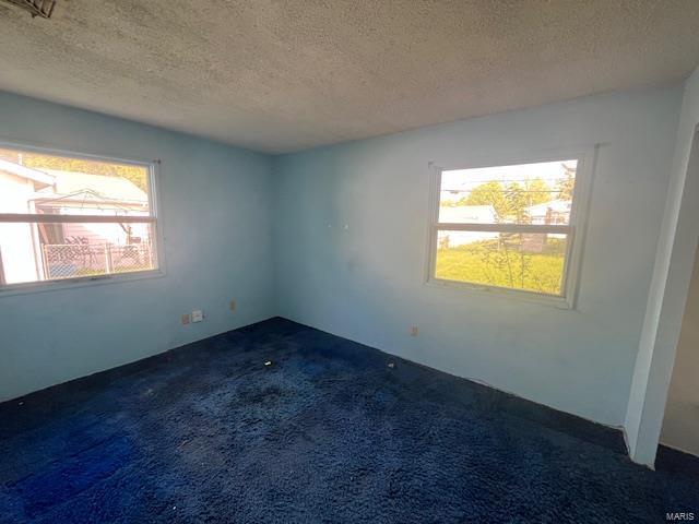 unfurnished room featuring dark colored carpet and a textured ceiling