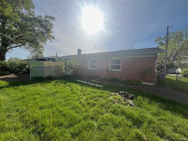 rear view of house featuring a yard and brick siding