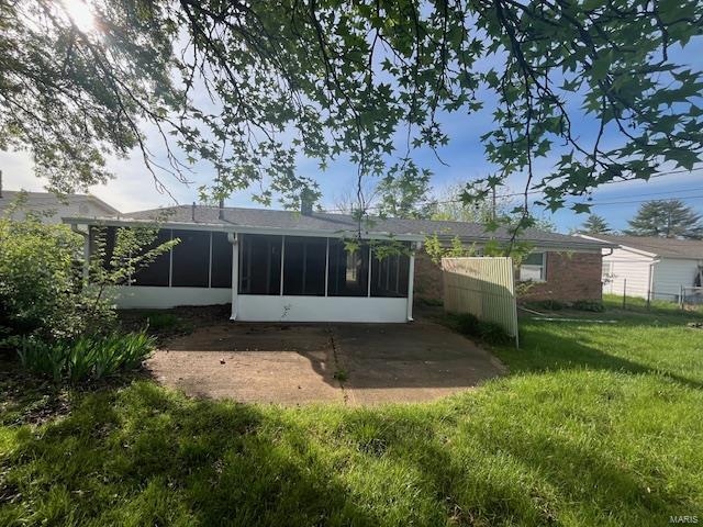 back of property with a patio area, a sunroom, and a lawn