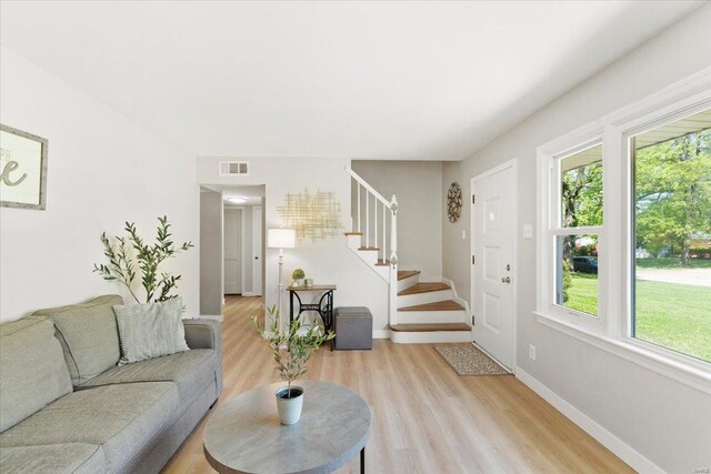 living area with stairway, plenty of natural light, light wood-type flooring, and visible vents