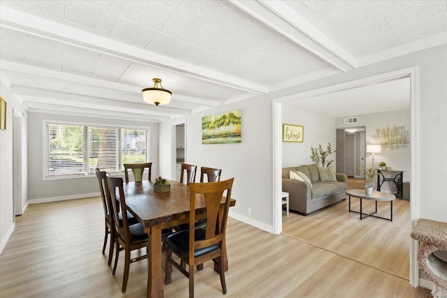 dining room with baseboards, beam ceiling, visible vents, and light wood-style flooring