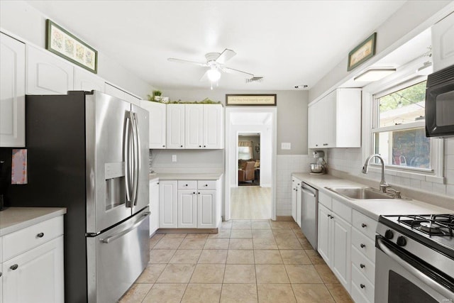 kitchen with a ceiling fan, a sink, light countertops, stainless steel appliances, and white cabinetry