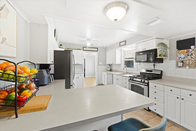 kitchen featuring decorative backsplash, a breakfast bar, white cabinets, a sink, and stainless steel appliances