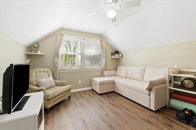living area with vaulted ceiling, baseboards, a ceiling fan, and light wood-type flooring