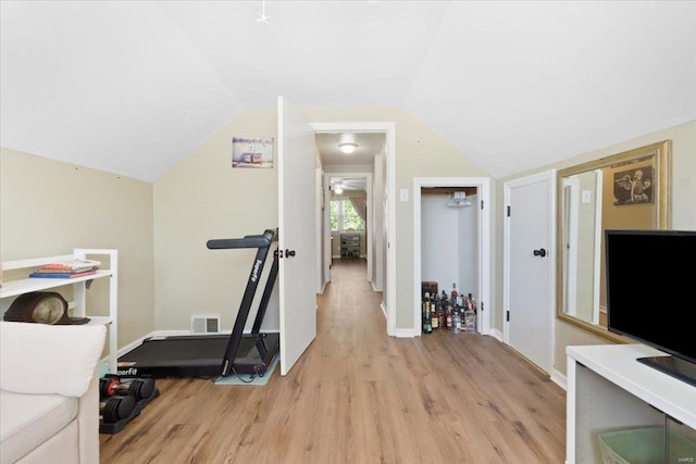 workout room featuring baseboards, visible vents, light wood-style flooring, and lofted ceiling